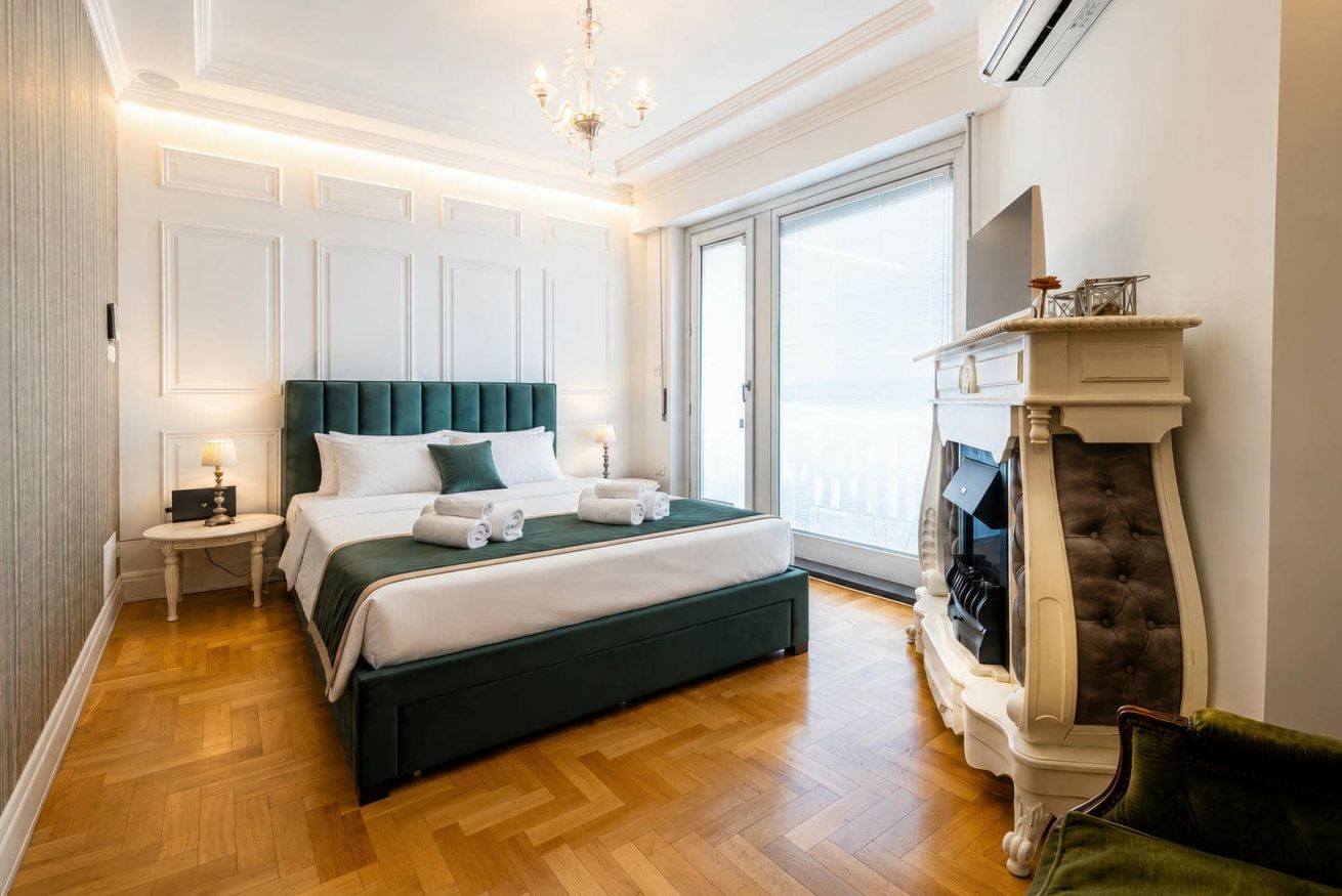 Elegante camera da letto moderna con letto matrimoniale, camino decorativo e parquet chiaro.