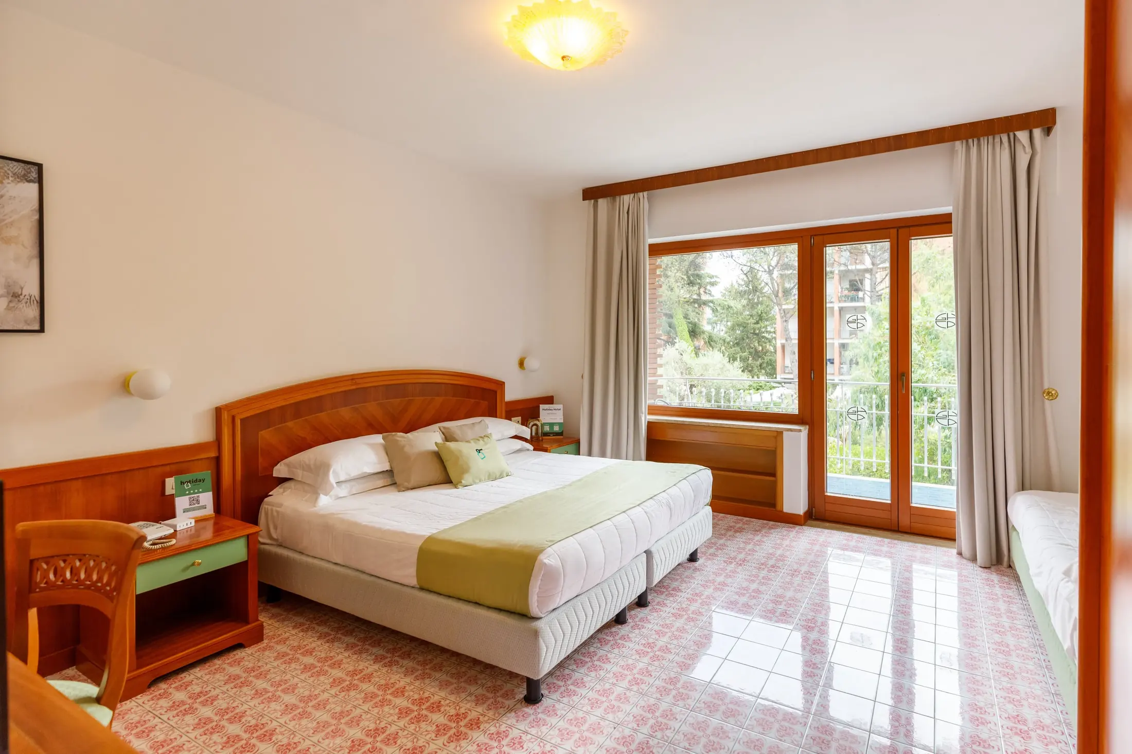 Camera d’albergo con letto matrimoniale, finestra a tutta altezza e scrivania laterale
