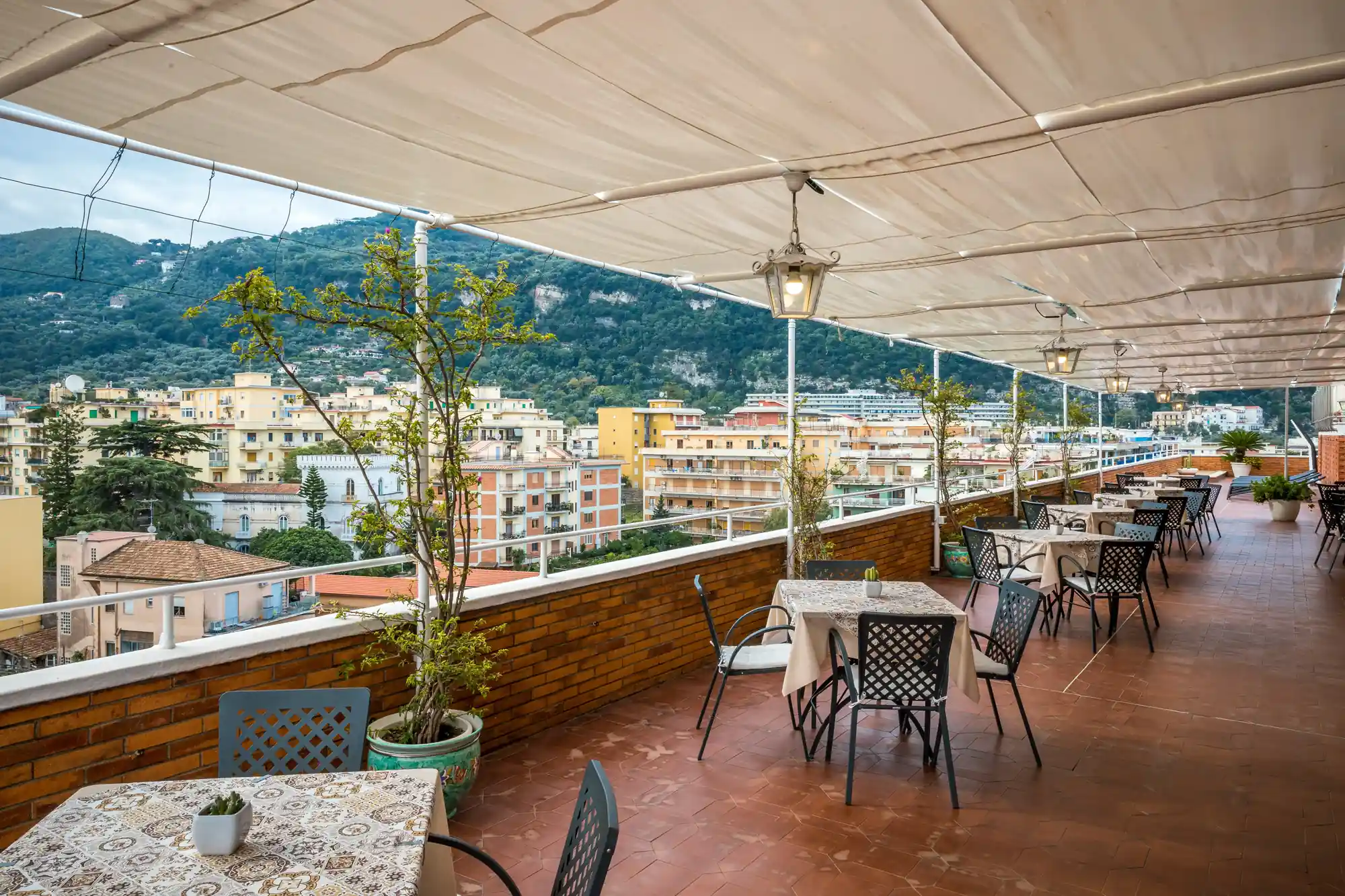 Terrazza panoramica di un ristorante con tavoli apparecchiati e vista sulla città e sulle montagne