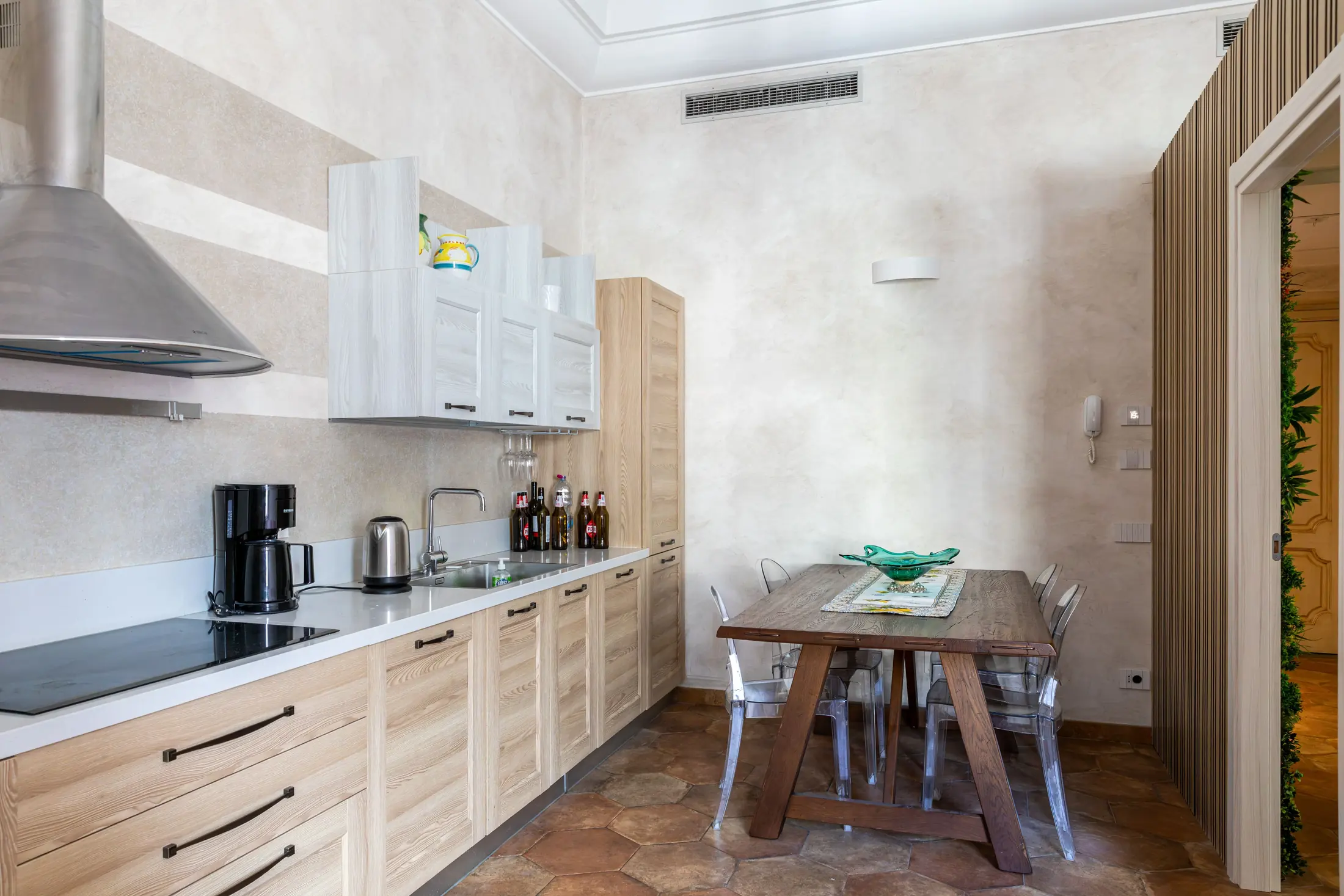 Cucina moderna con tavolo da pranzo, mobili in legno chiaro e piano cottura a sinistra