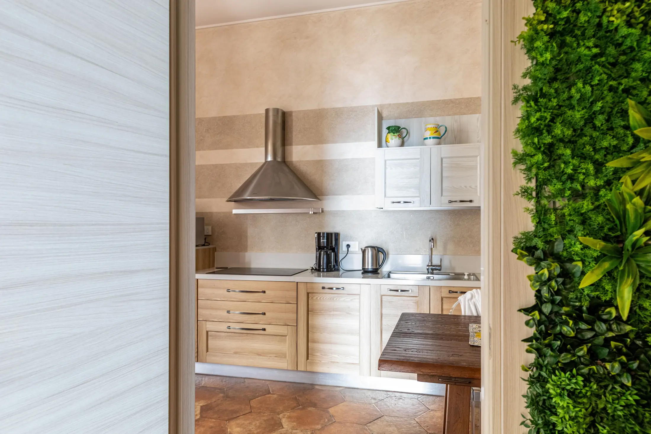 Cucina moderna con mobili in legno, cappa in acciaio e parete verde decorativa