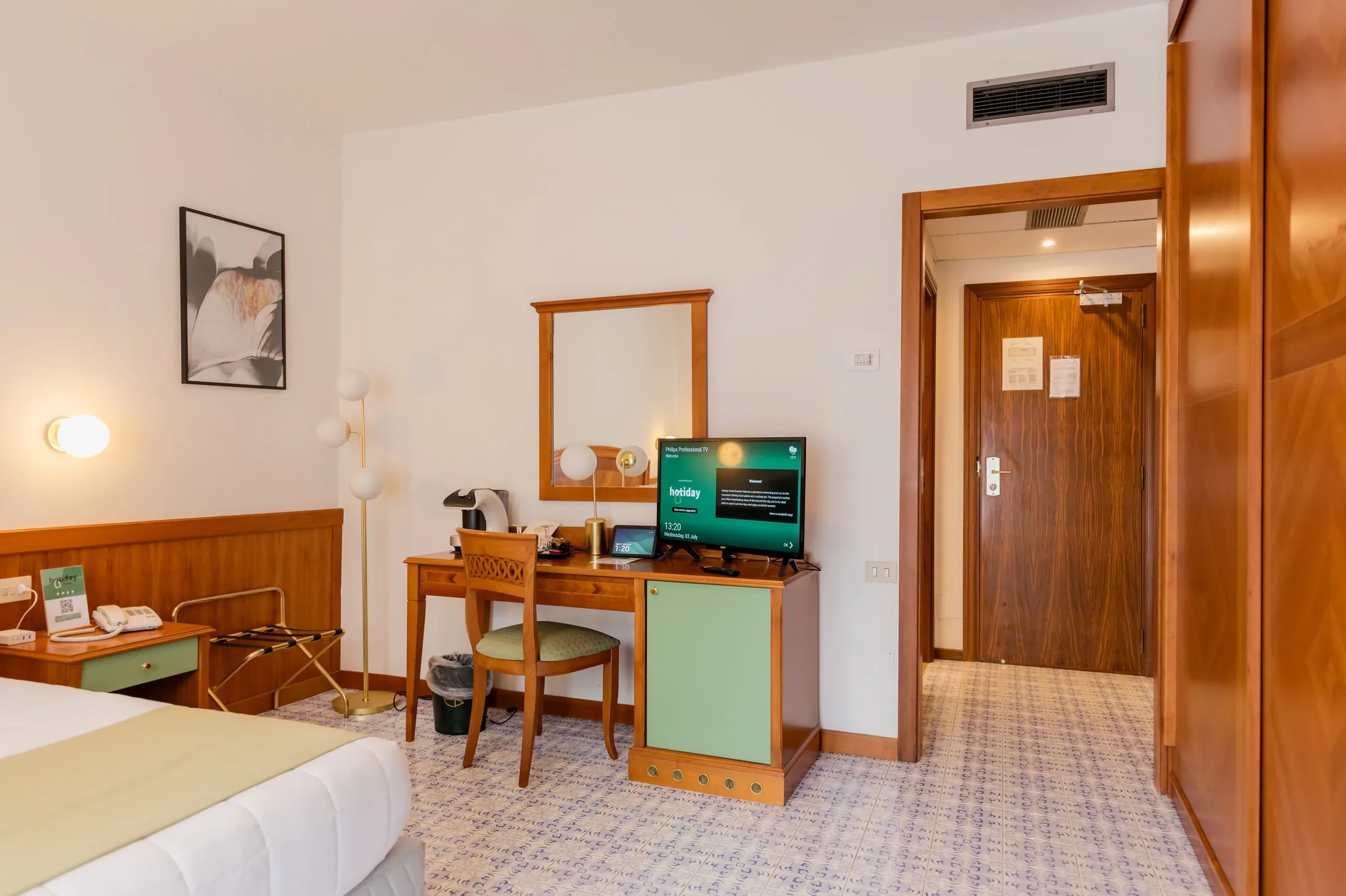 Camera d’albergo con letto, scrivania, TV e bagno all’ingresso