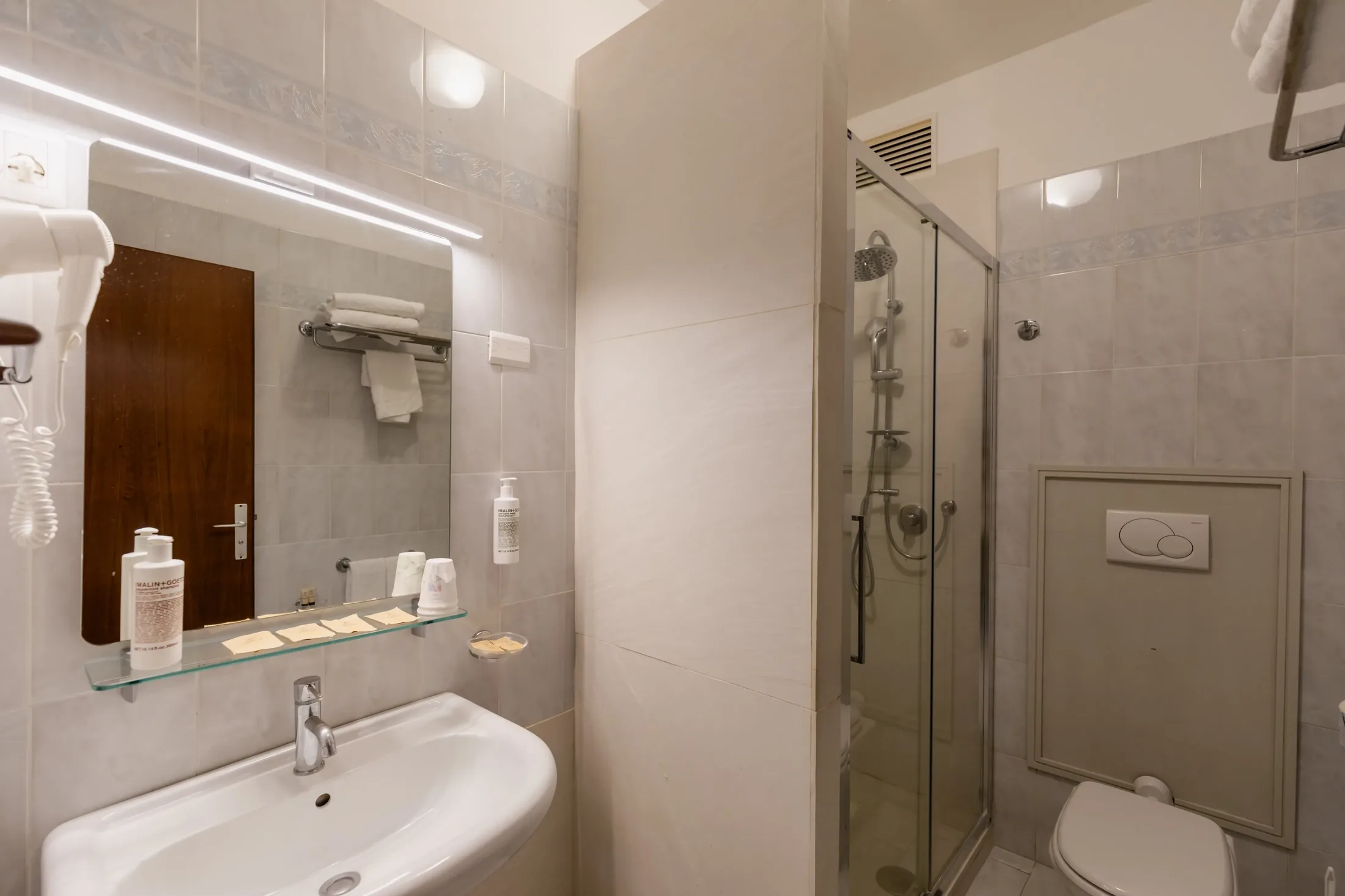 Bagno con lavabo, specchio, doccia in vetro e WC