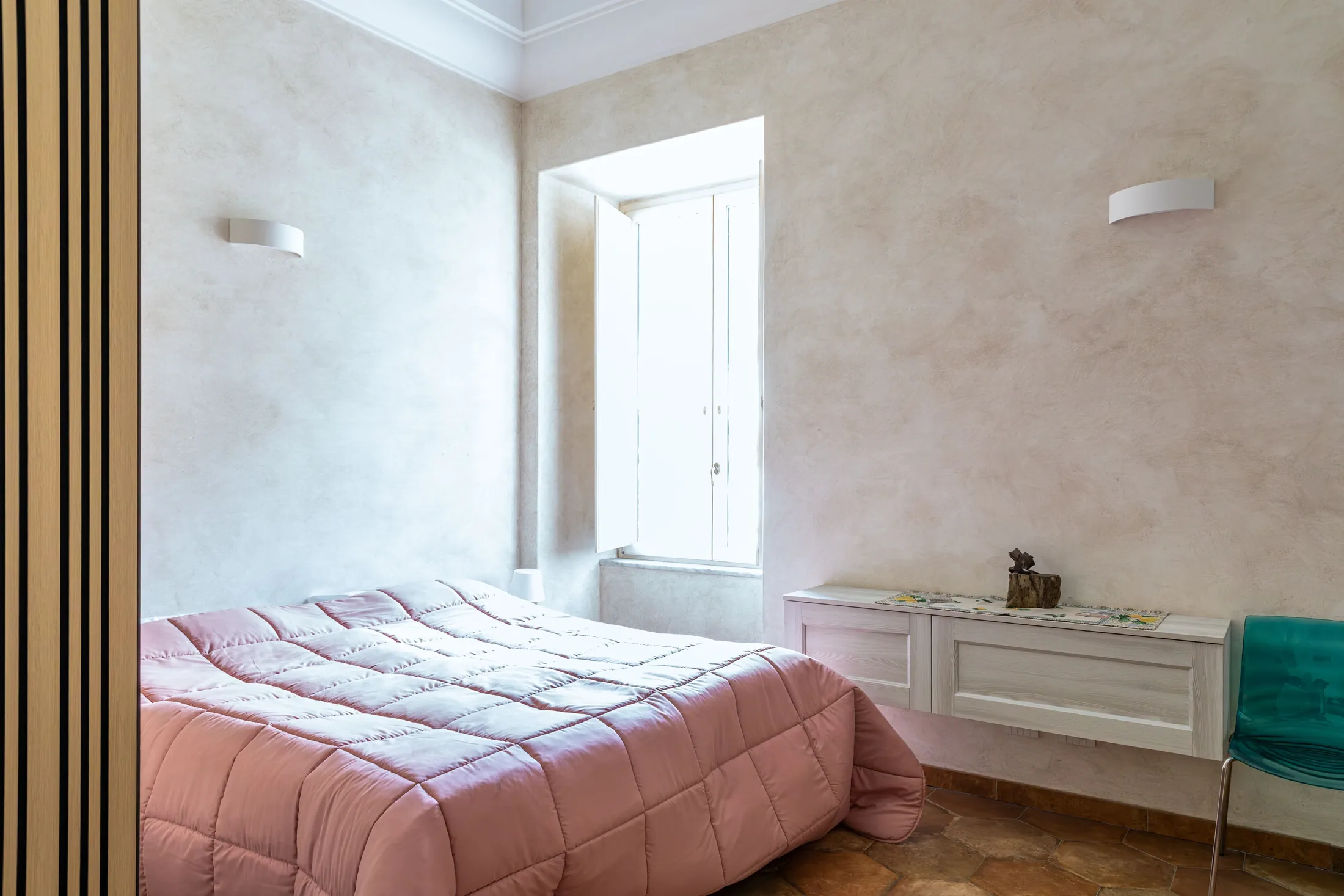 Camera da letto luminosa con letto matrimoniale rosa, finestra aperta e cassettiera bianca