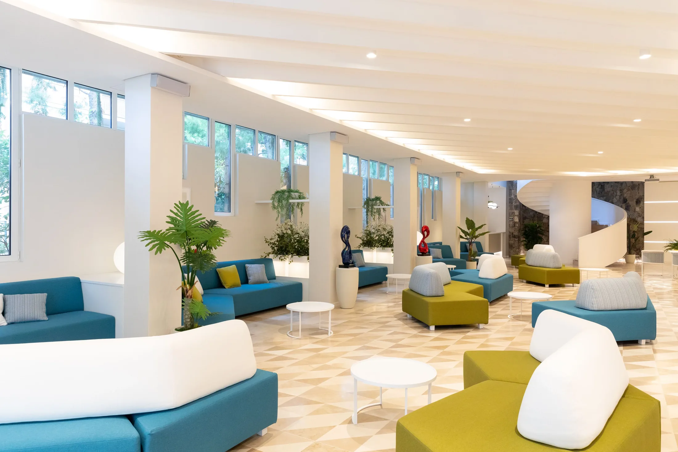 Ampia lounge moderna e luminosa con divani colorati, tavolini e grandi finestre