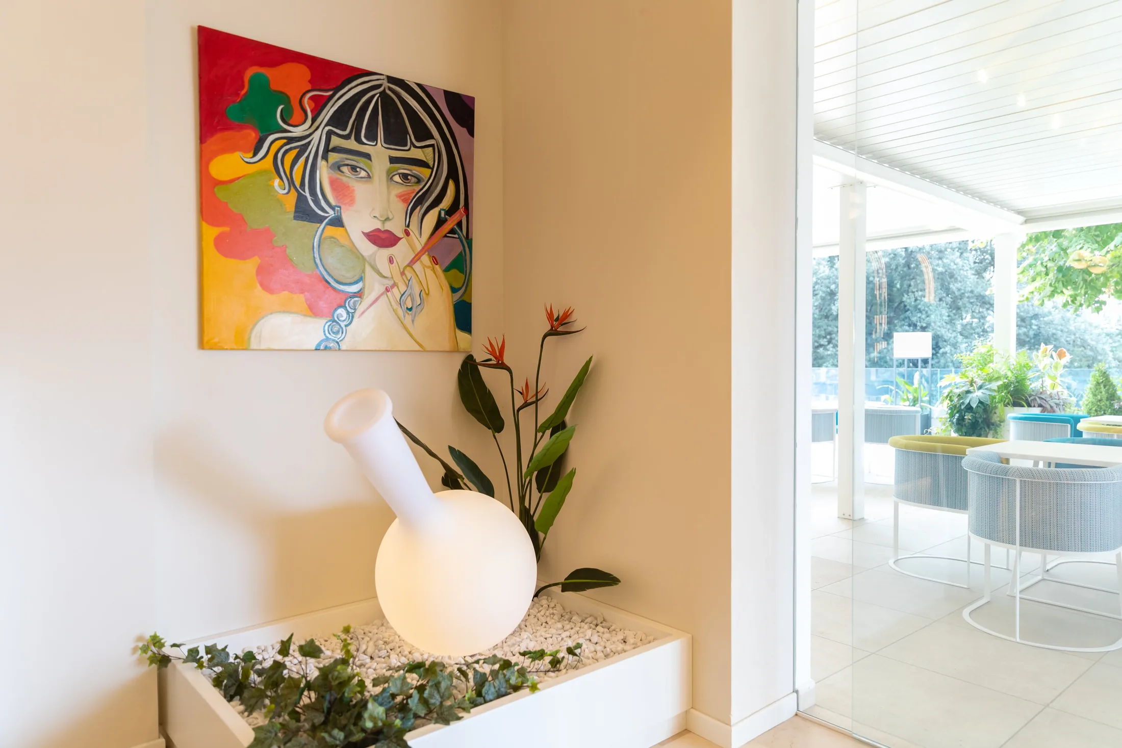 Interno moderno con quadro colorato, vaso bianco e vista su una terrazza luminosa